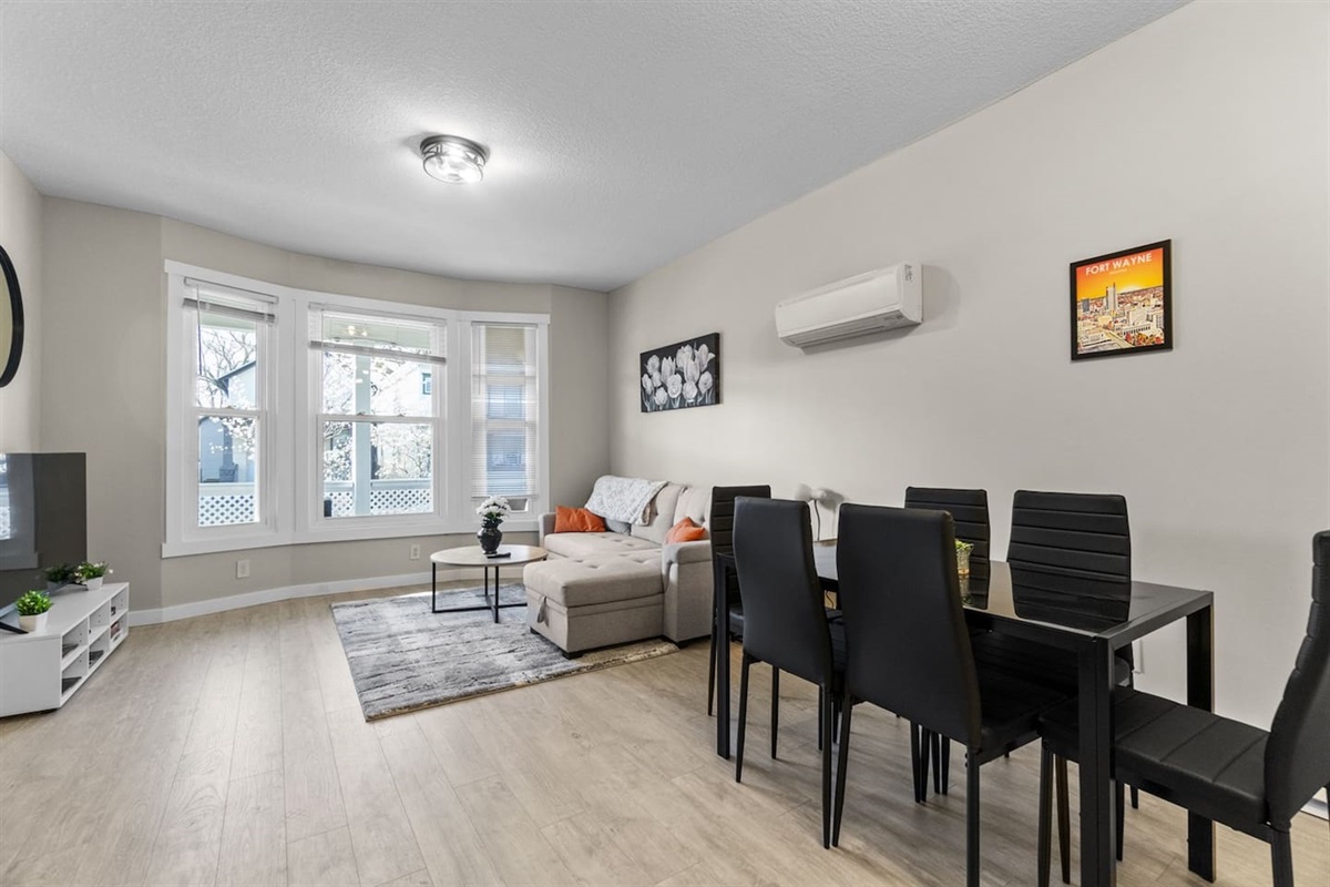 Bright and airy living and dining room filled with abundant natural light from large windows.