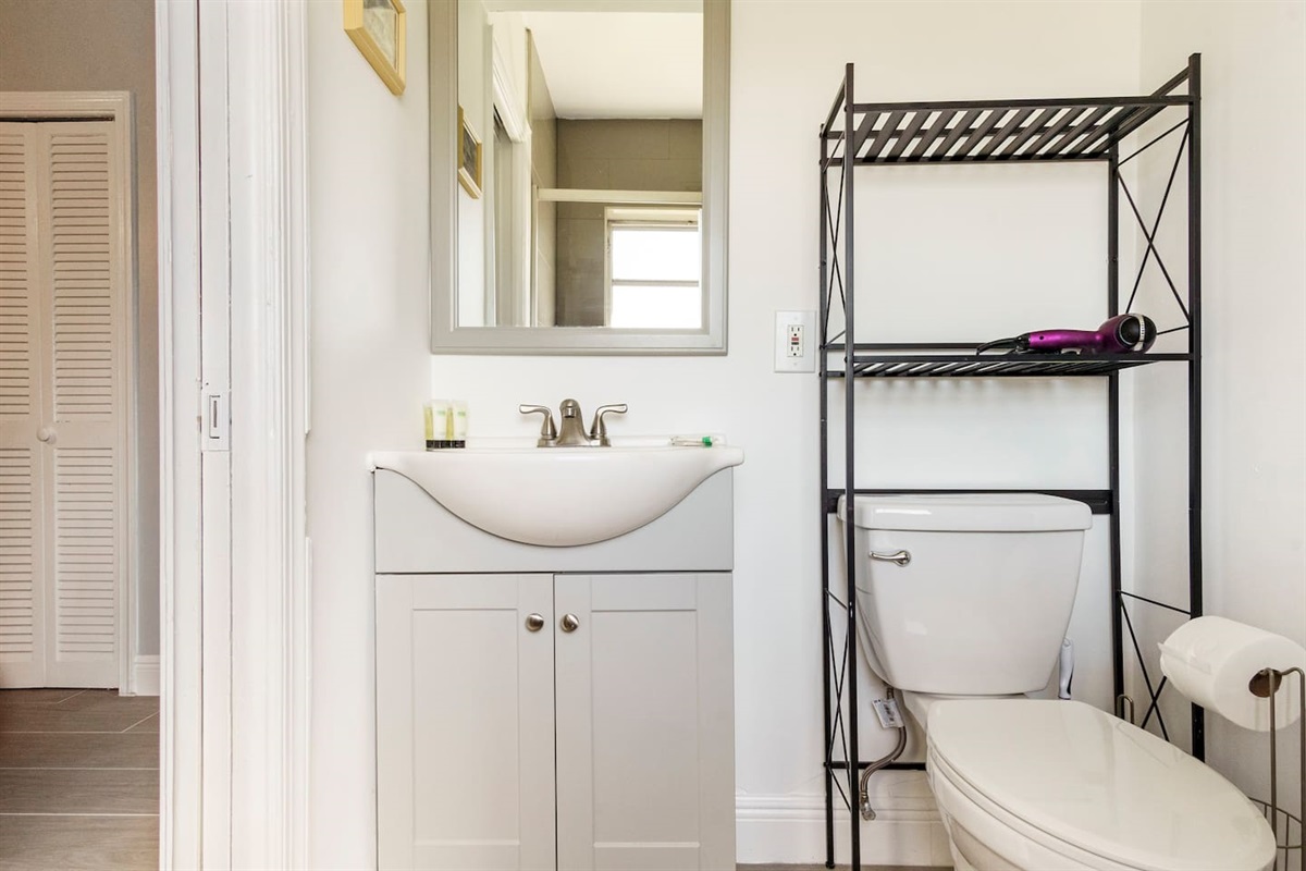 This "Jack and  jill" bathroom has a newly tiled frameless shower, lots of natural light, and ample storage.