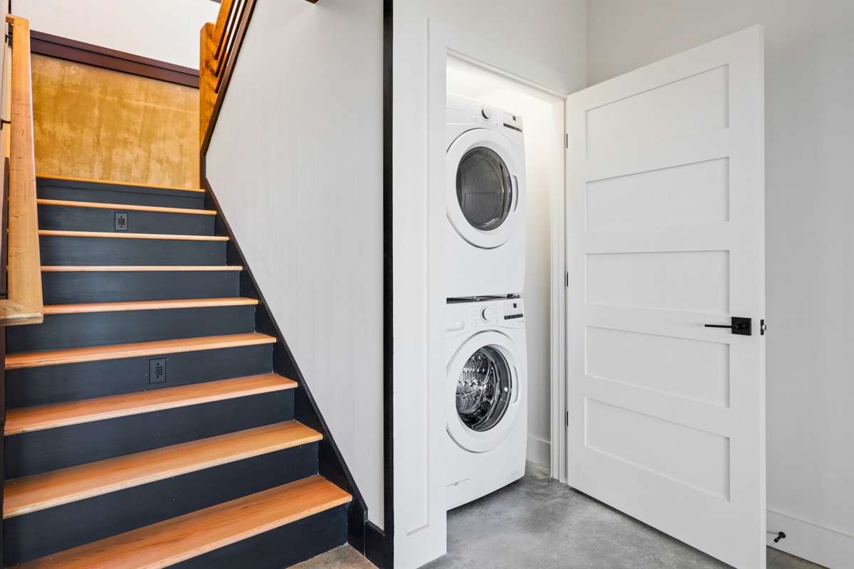 Efficiency meets design in this downstairs laundry nook, where modern appliances are tucked away neatly beside a stylish staircase.