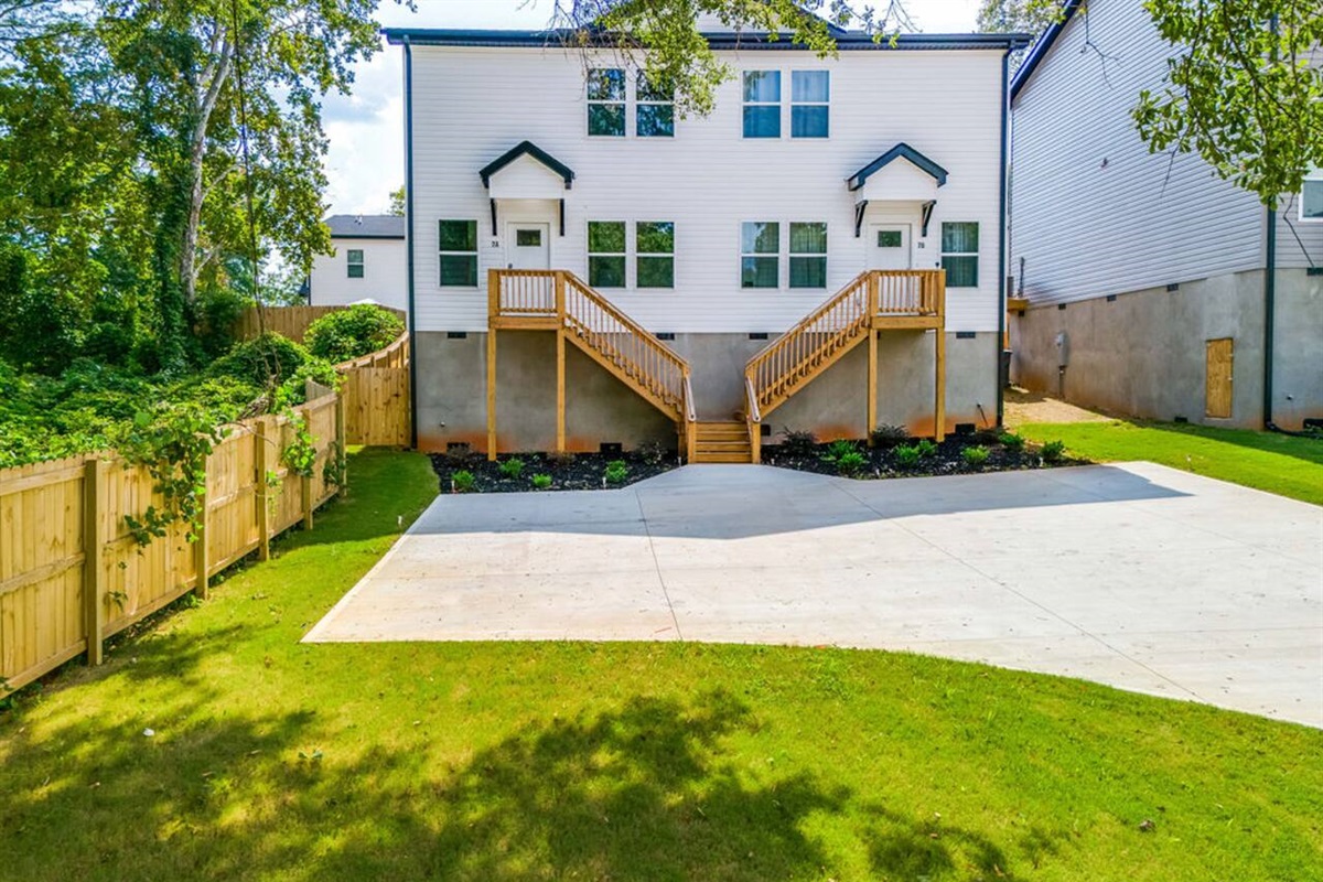 Well-maintained front yard with lush green grass, a driveway, and a cement parking pad for convenient parking access.