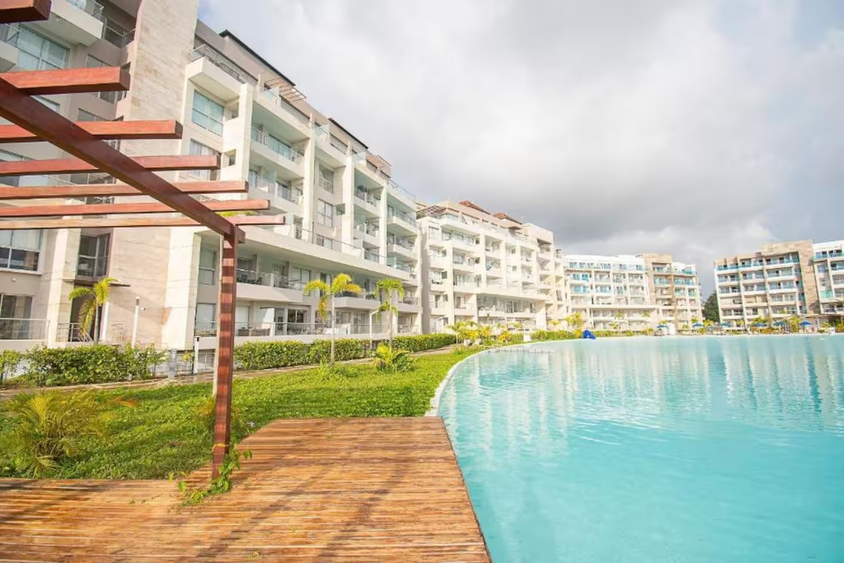 Las amenidades tipo resort incluyen una amplia piscina estilo laguna, zonas de arena junto a la piscina, acceso al spa, áreas lounge con sombra y asientos exteriores para disfrutar de momentos de descanso.