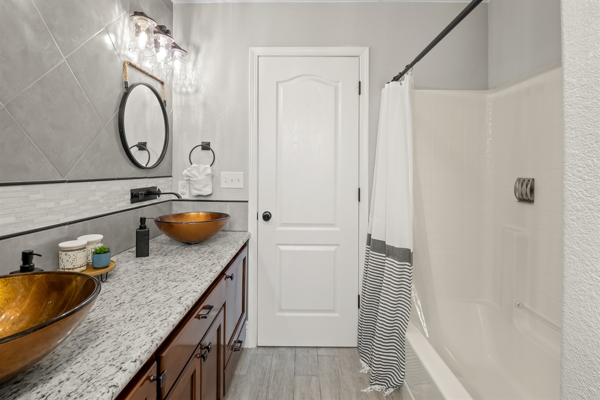 Stylish double-vanity bathroom with statement vessel sinks, granite counters, and a clean, modern shower—designed for comfort and convenience.