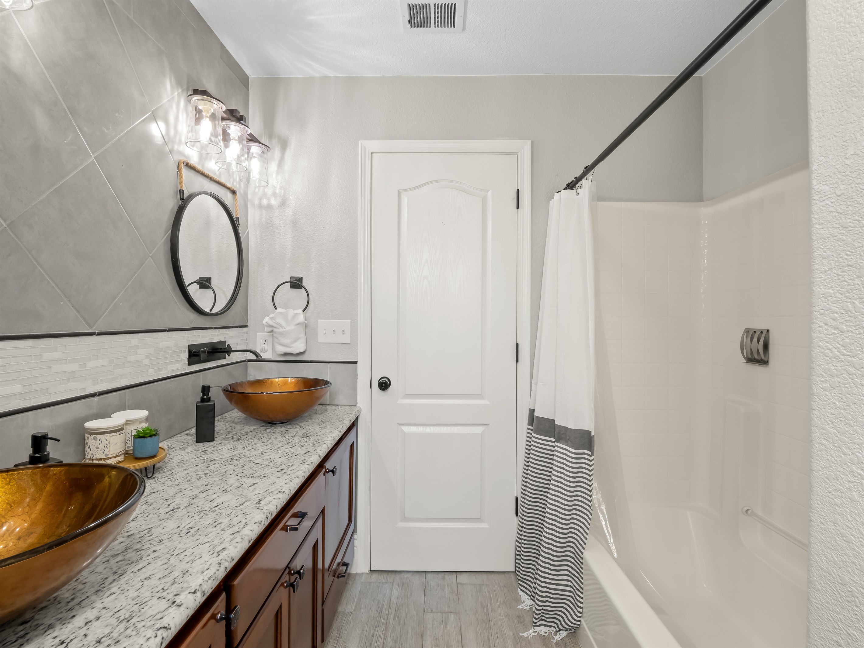 Stylish double-vanity bathroom with statement vessel sinks, granite counters, and a clean, modern shower—designed for comfort and convenience.