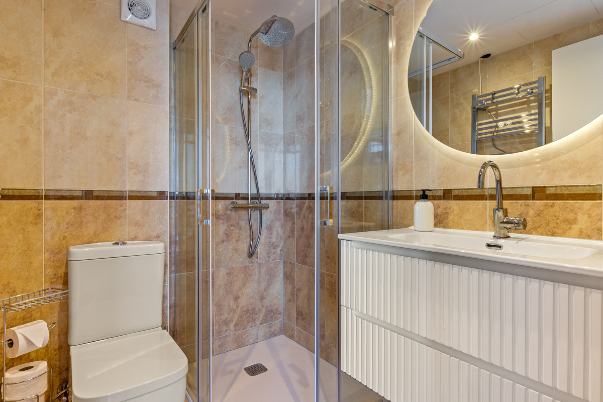 Second full bathroom with walk-in shower and illuminated mirror.