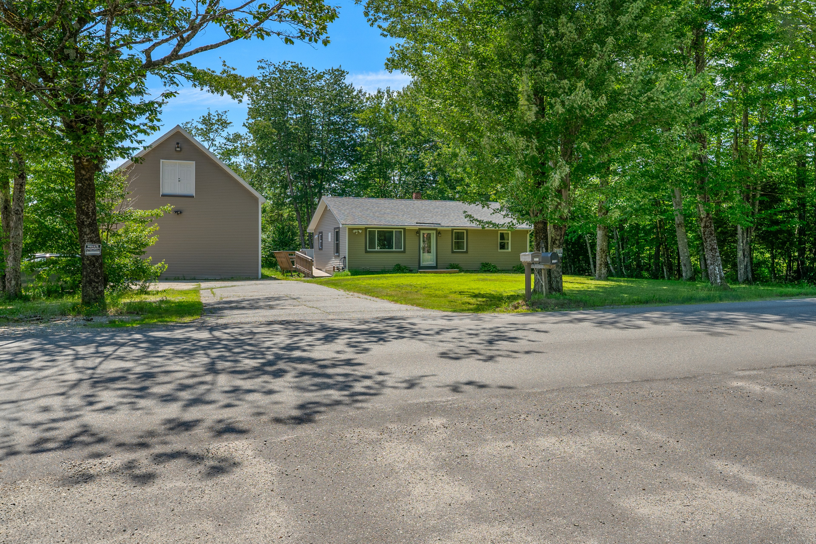 Pull directly into the wide, paved driveway providing plenty of space for multiple vehicles. This entry point connects to the gravel loop for pull-through trailer parking, offering convenient maneuverability for boats, ATVs, and large rigs.
