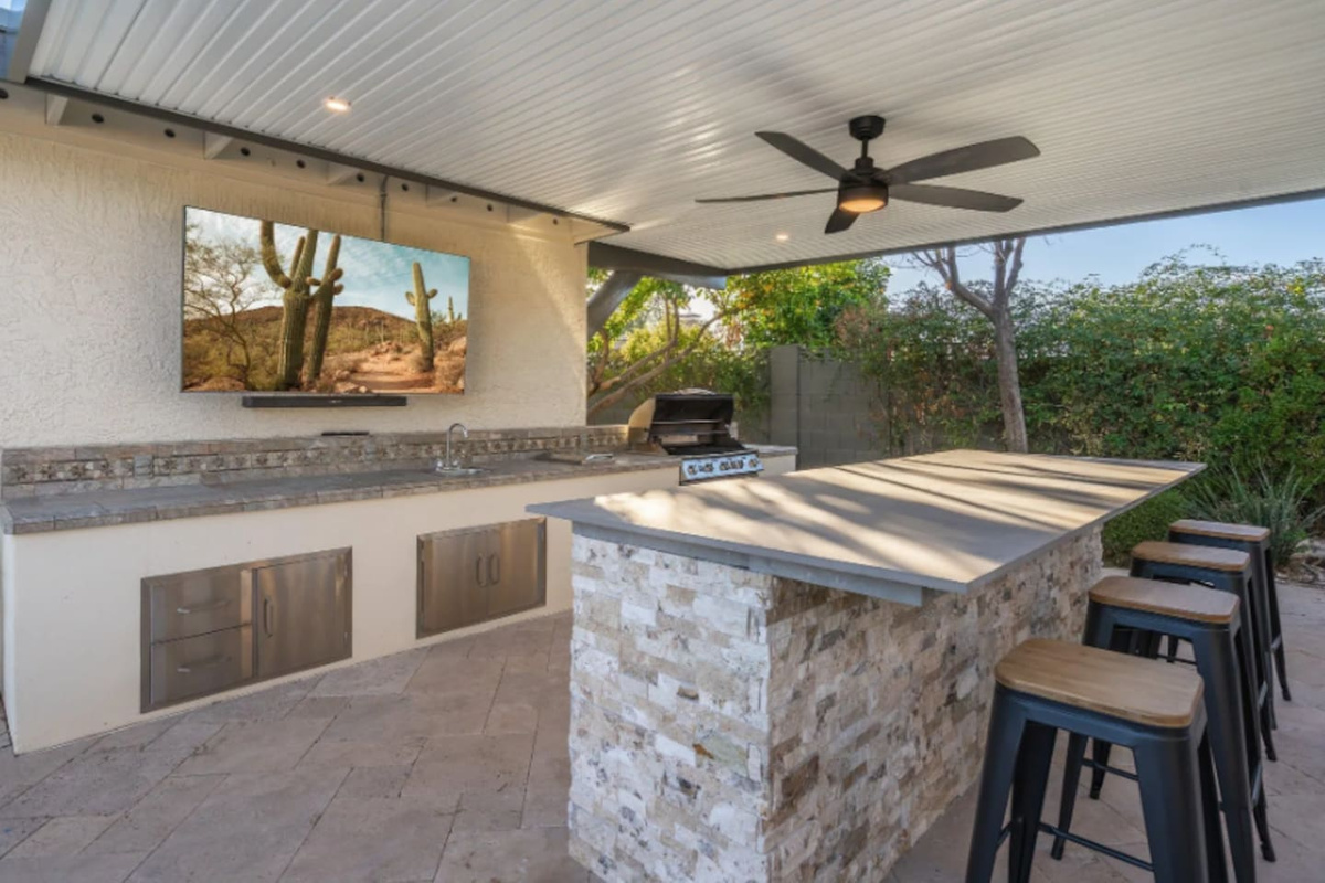 A fully equipped outdoor kitchen turns grilling into the main event, with bar seating and a mounted TV so no one misses the game. Built-in storage keeps everything tucked away and ready to go.
