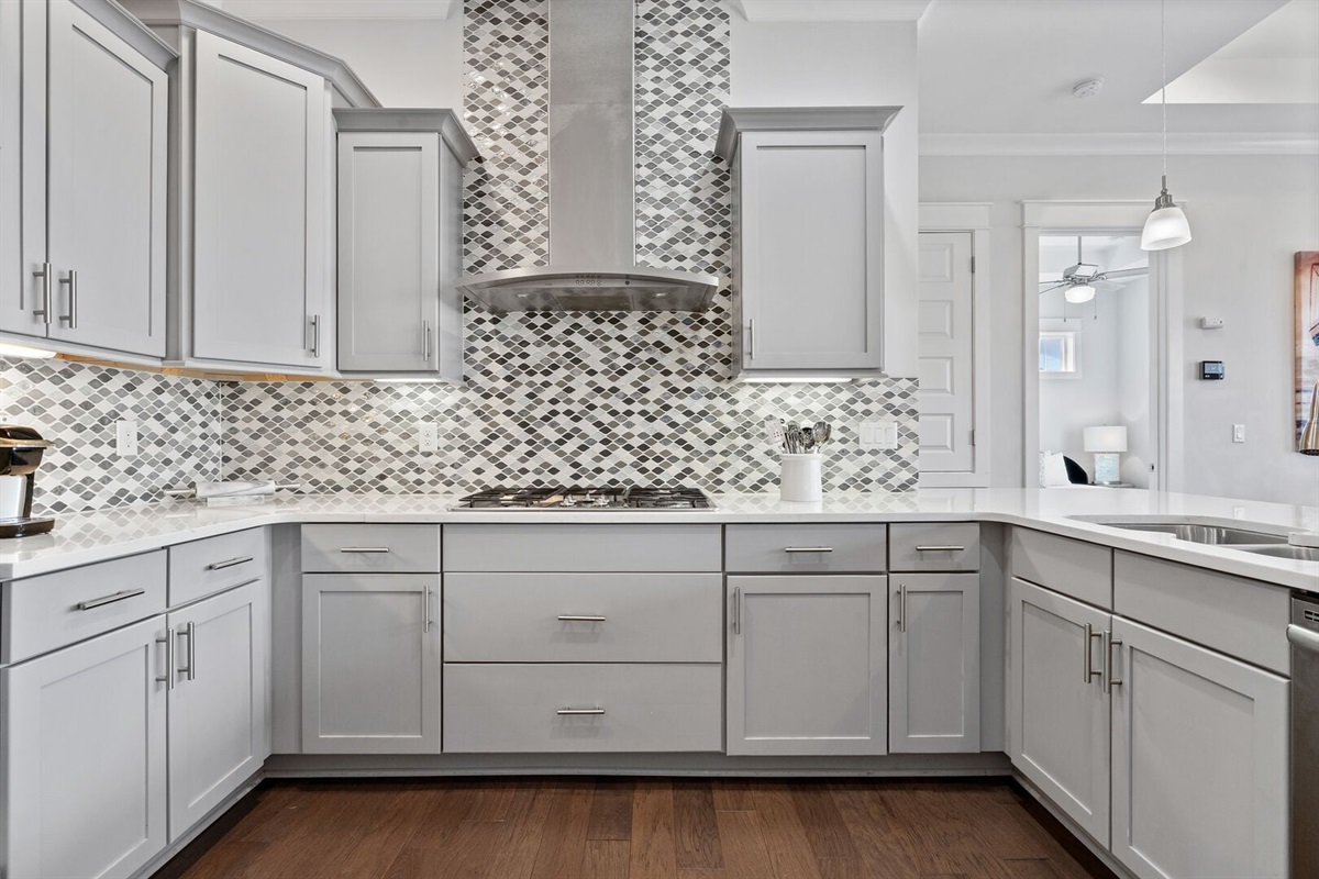 Gas cooktop with mosaic tile backsplash.