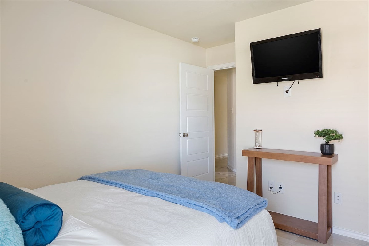 Step into this cozy bedroom featuring a wall-mounted TV and a sleek wooden console for your convenience.