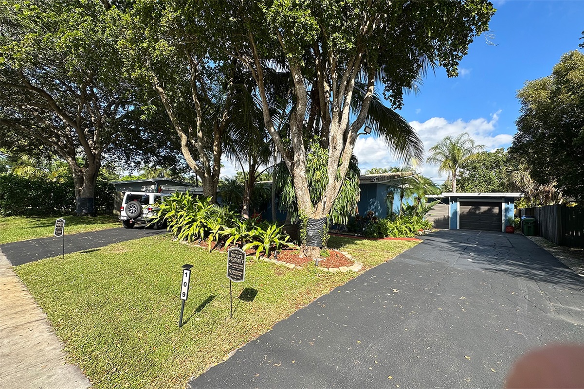 Garden of Manors exterior with tropical greenery, private driveway access, and a relaxed South Florida atmosphere.