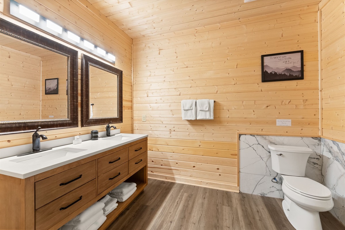 Lower-level full bathroom featuring dual vanity sinks, elegant mirrors, and a spa-like shower area for added comfort and convenience.