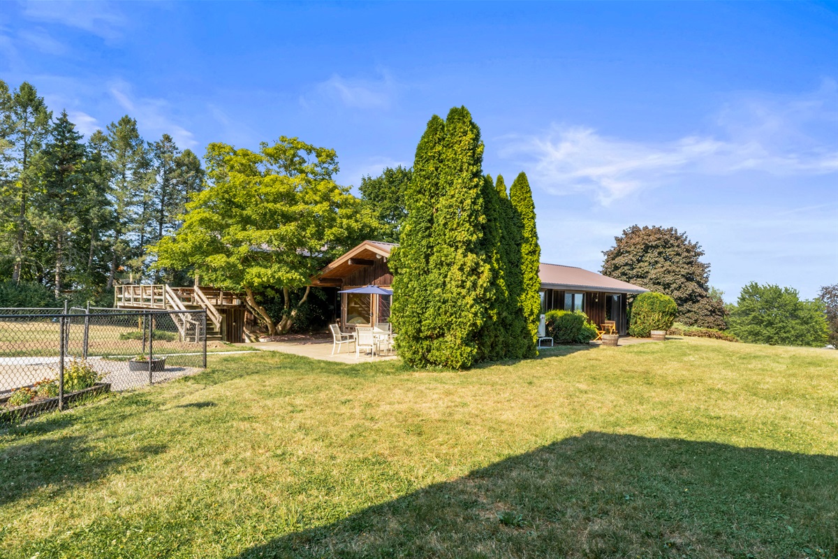 Spacious backyard retreat featuring mature trees, outdoor seating, and plenty of room for relaxation or entertaining.