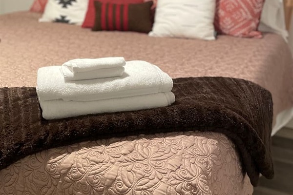 A fresh stack of clean towels ready for use, adding a touch of comfort and care to the bedroom.