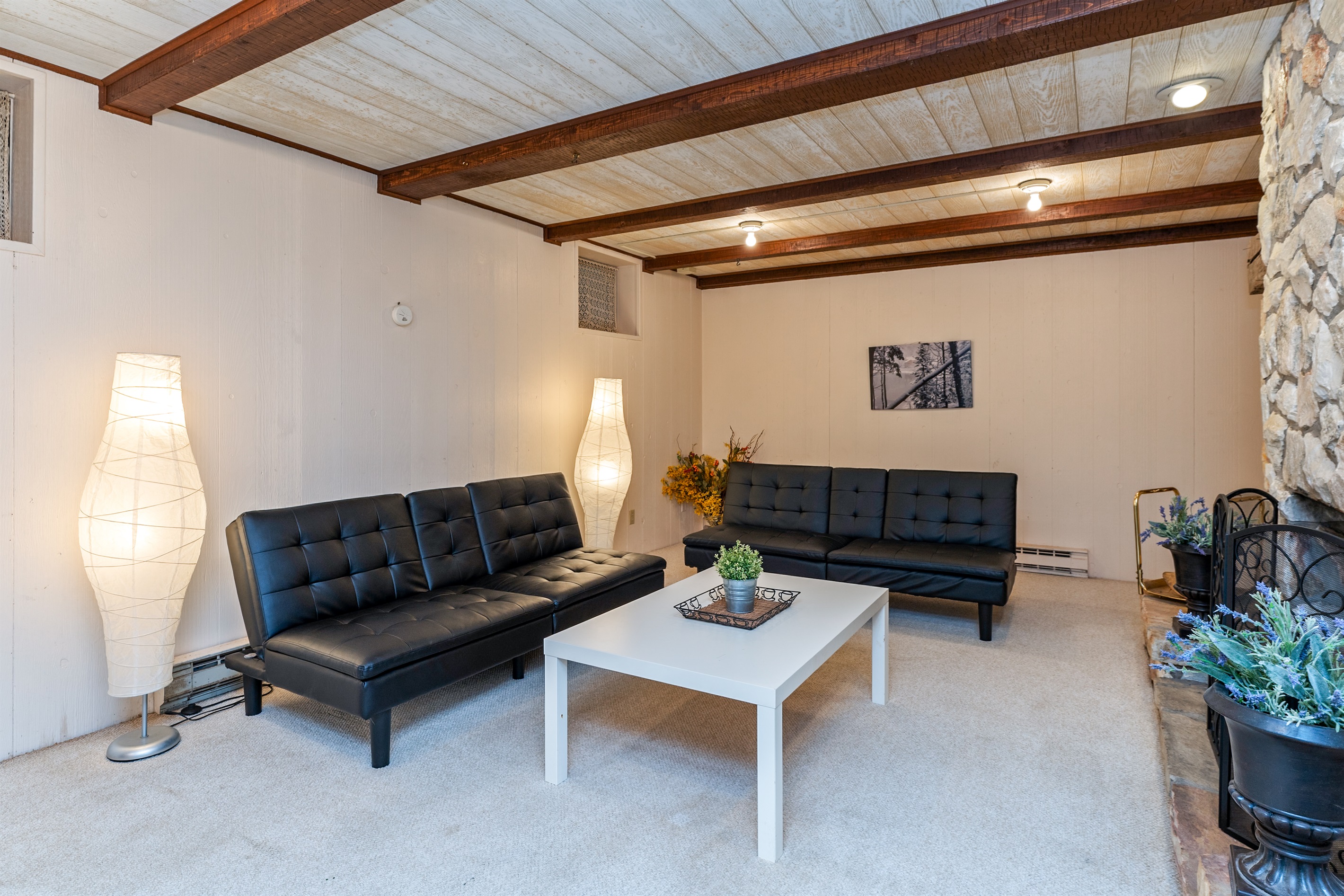 Unwind in the inviting basement level living room with plush seating and a stunning stone fireplace – a perfect spot for cozy evenings.