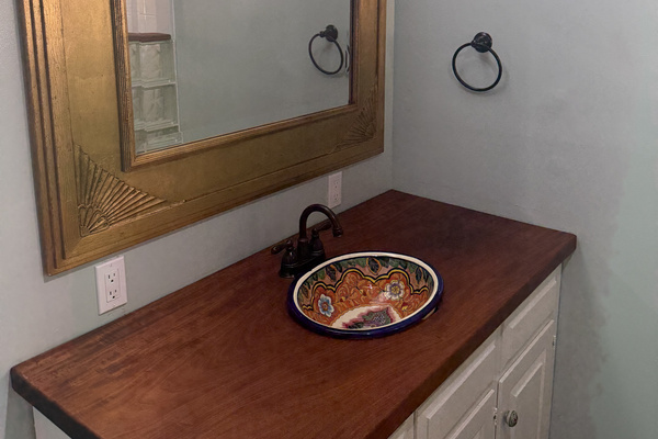 Primary bathroom features a handcrafted Talavera ceramic sink, locally sourced mahogany countertop, and unique artisanal fixtures for a perfect blend of tropical warmth and character.