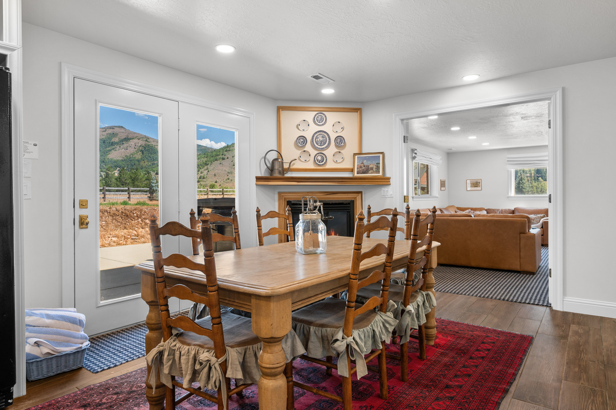 The lower-level dining area blends elegance with practical comfort, featuring natural wood furnishings, a rich patterned rug, and mountain views.