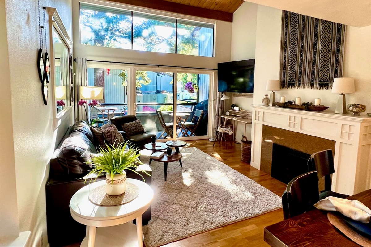 Living room with full wall of windows so you can enjoy the greenery on a sunny day or sit by a cozy fire on quiet fall and winter days