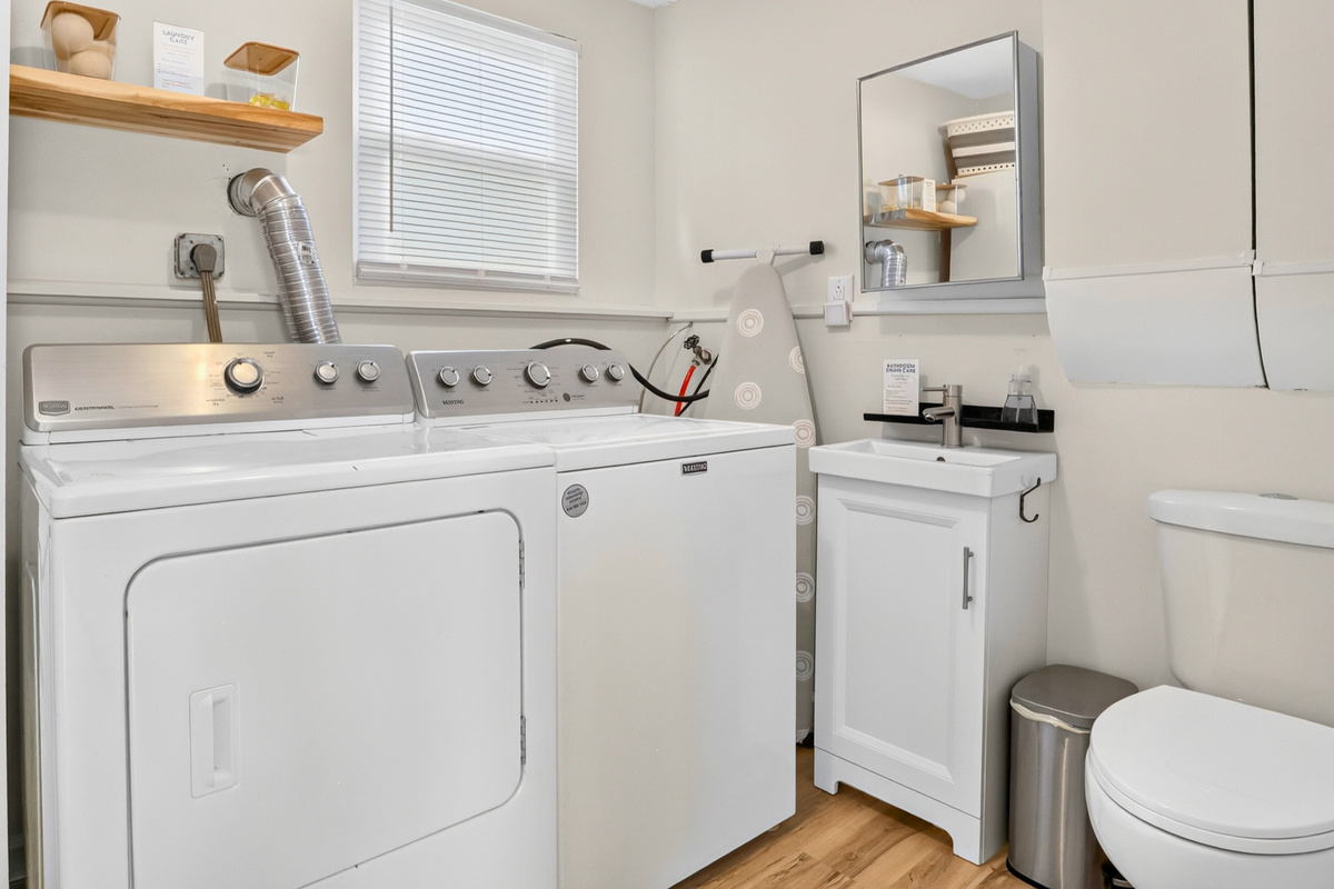 Laundry room with a convenient half bath, ironing essentials, and starter laundry supplies.