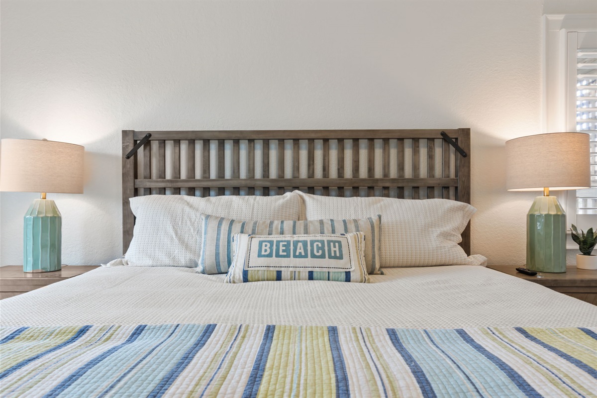 Close-up view of the bed setup, showing bedding details and bedside lighting.