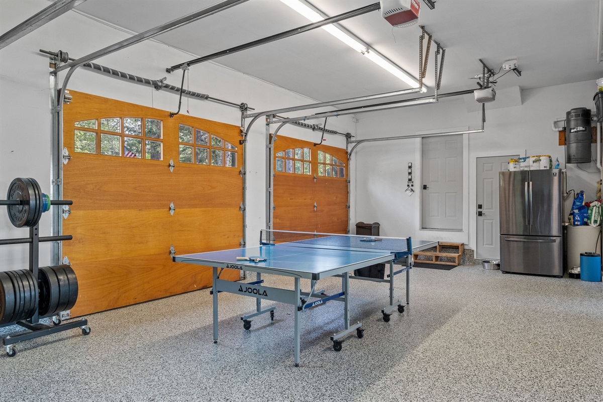 Garage with ping pong, parking for 3 cars, ev chargers, treadmill, and weights, also has a black light system and a bluetooth speaker