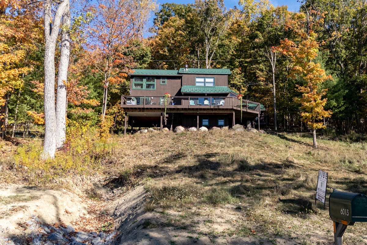 Exterior view of cabin from a hill above showing deck and lakeside proximity.