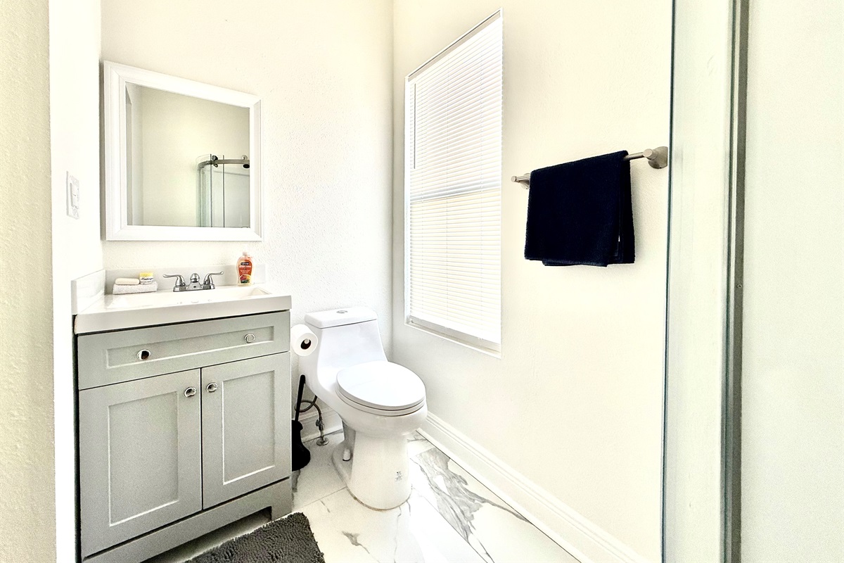 Compact yet stylish, this bathroom features a sleek glass-enclosed corner shower with built-in shelves and premium soap dispensers—ideal for a refreshing rinse after a day of adventure.