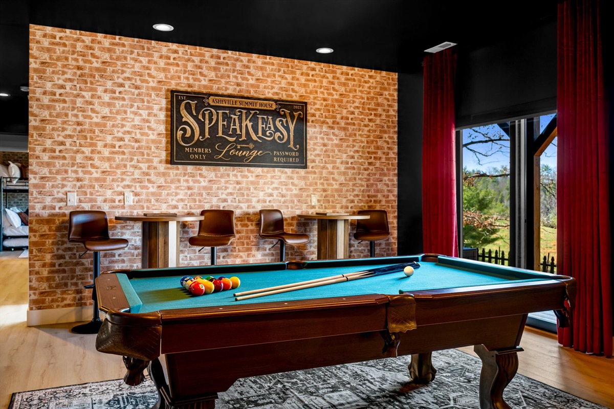 {Game Lounge} Unwind in our moody speakeasy-style lounge featuring a classic pool table, warm brick accents, and curated lighting. Perfect for late-night games, cocktails, and relaxed group hangouts, this space brings a unique, upscale twist to your stay.