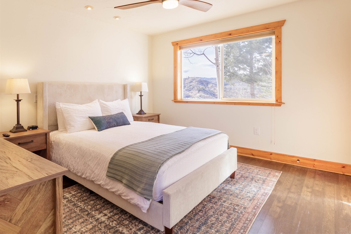 Primary bedroom offers a cozy queen bed and expansive wilderness views