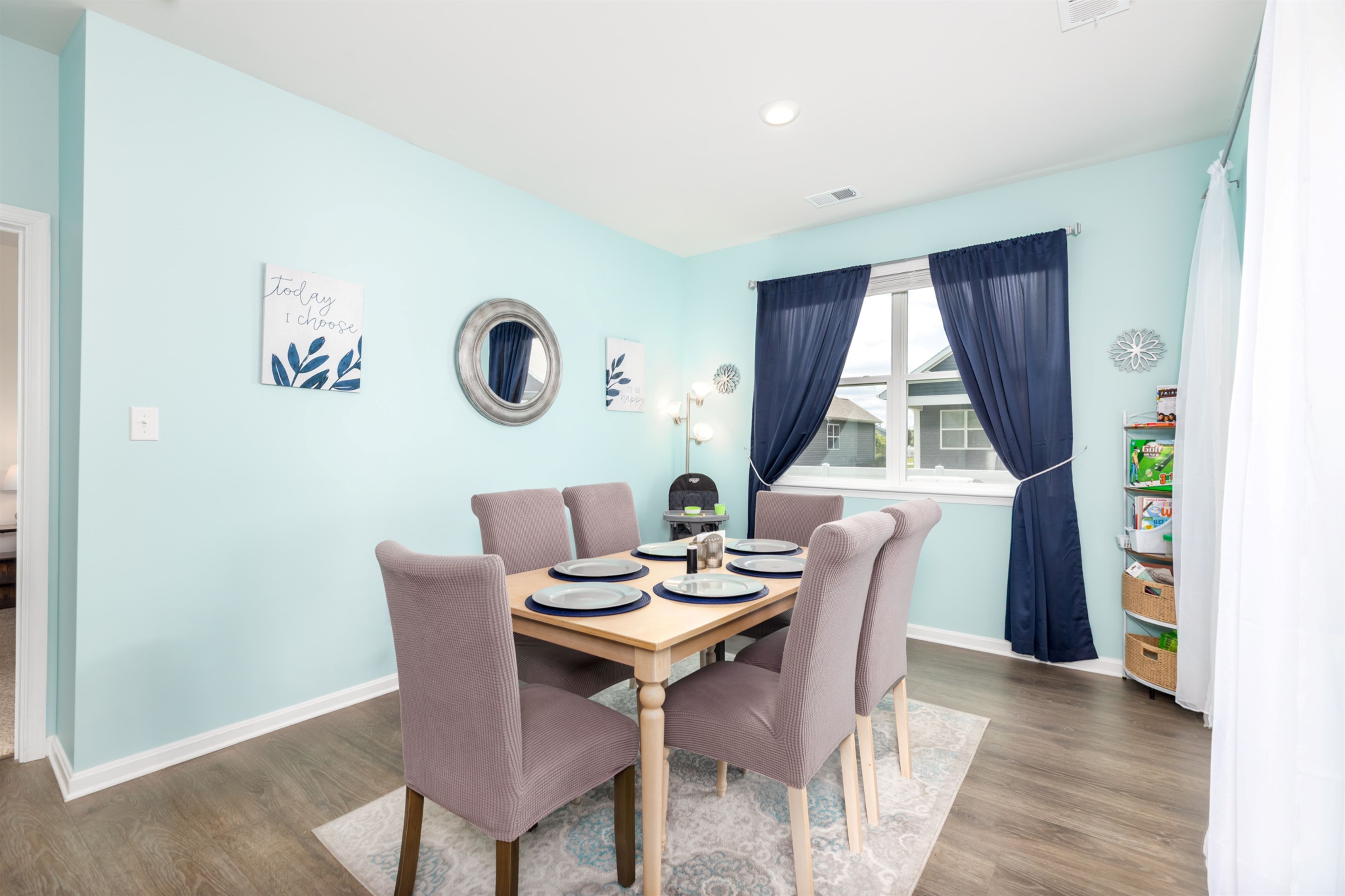 Cozy coastal dining nook with seating for six, complete with a toddler high chair and kids’ activity shelf—perfect for family meals, games, or planning your day’s beach adventures.