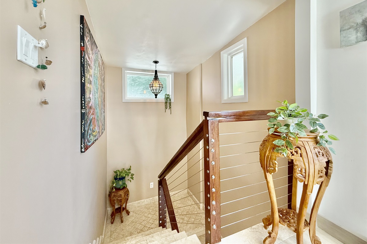 Head straight out of the primary bedroom and you will go down a set of stairs to the main living area and kitchen.