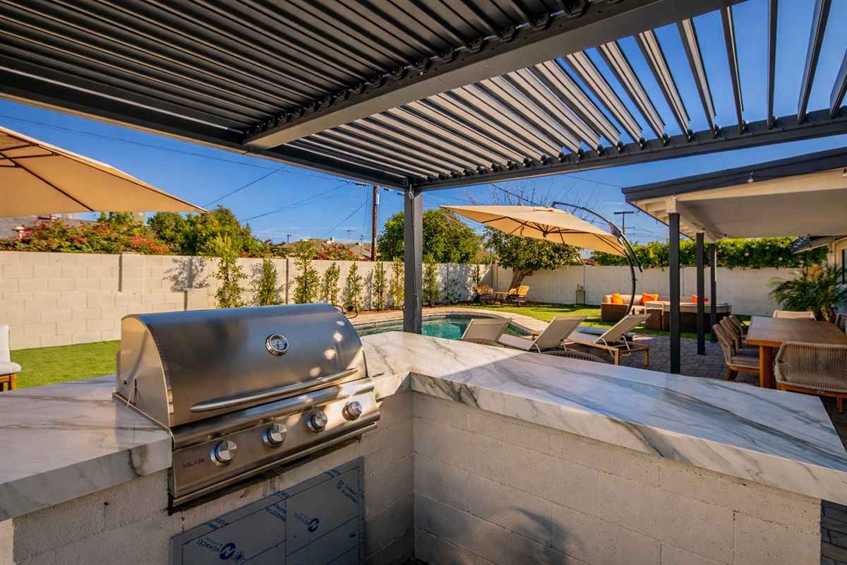 Outdoor kitchen with built-in grill, prep space, and shaded pergola — perfect for BBQs, entertaining, and outdoor dining in Scottsdale.