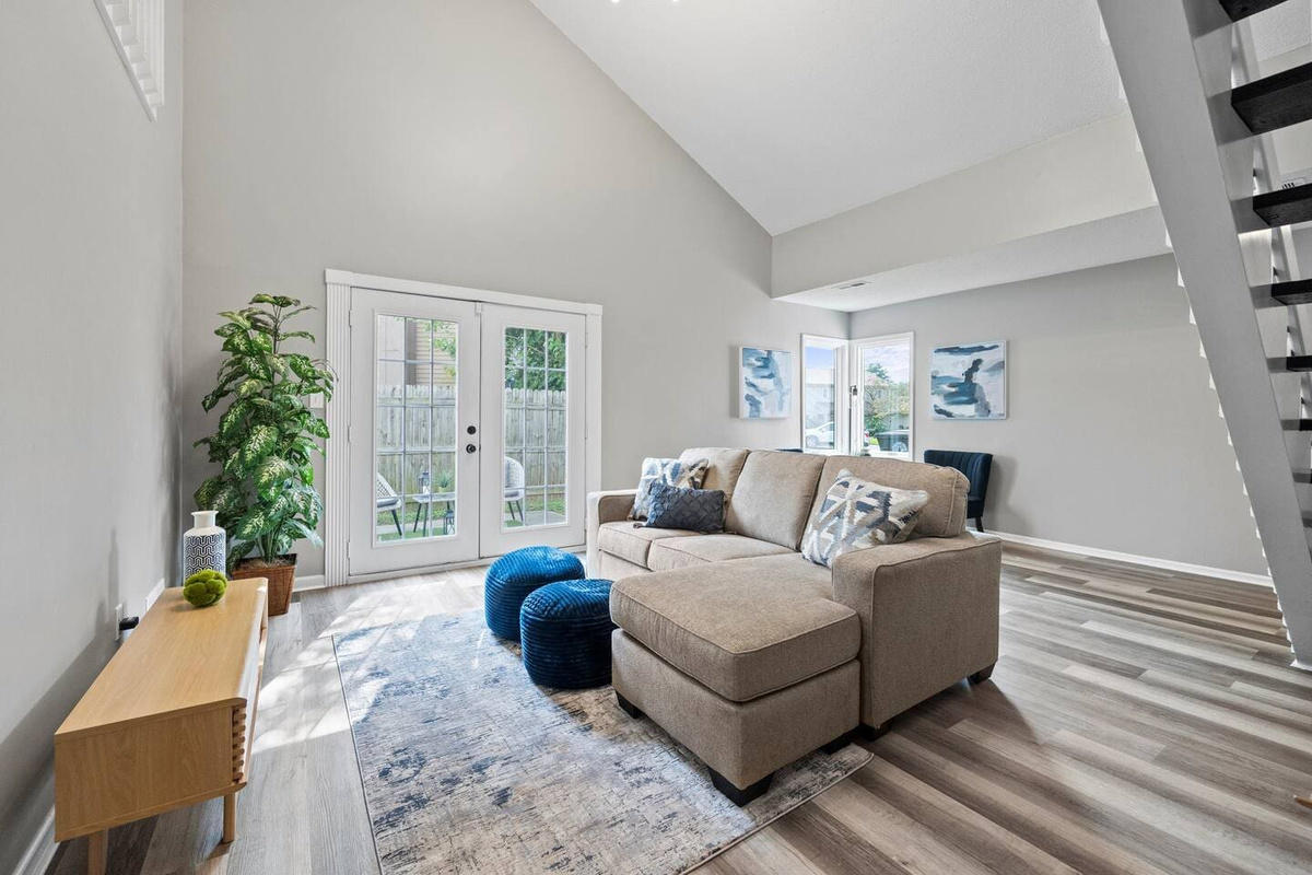 Inviting living area featuring comfortable couches, bathed in soft natural light from large windows, creating a warm and relaxing ambiance.