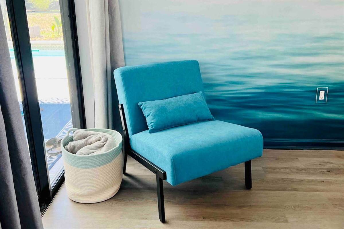 Every detail pops at this artistic Spring Hill Airbnb! Featuring a modern chair overlooking the pool that blends in with the wall mural- perfect for photo ready stays! #instaworthyvibes #aestheticstay #springhillAirbnb 