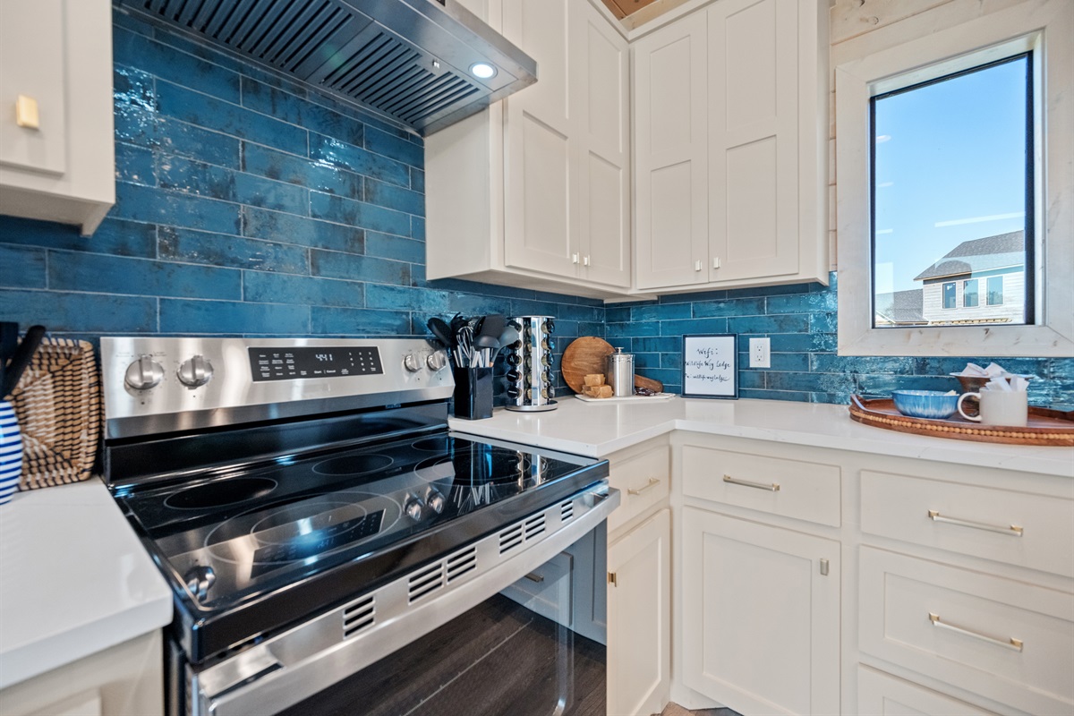Fully equipped kitchen with stainless steel stove and striking blue backsplash.