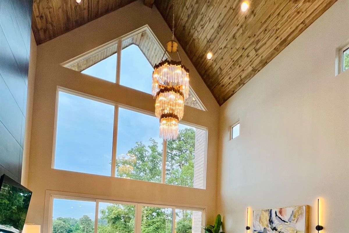 The stunning chandelier and high wood ceilings add a touch of glamour to the living room, making it a focal point of the house.
