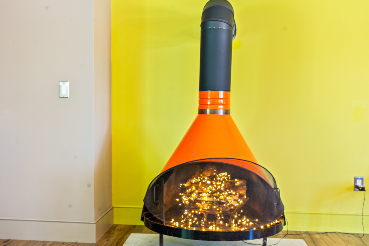 Retro aesthetic meets cozy ambiance. A bold orange mid-century cone fireplace serves as a decorative focal point at "The Crag," glowing with warm interior fairy lights to create an inviting evening atmosphere (decorative only).