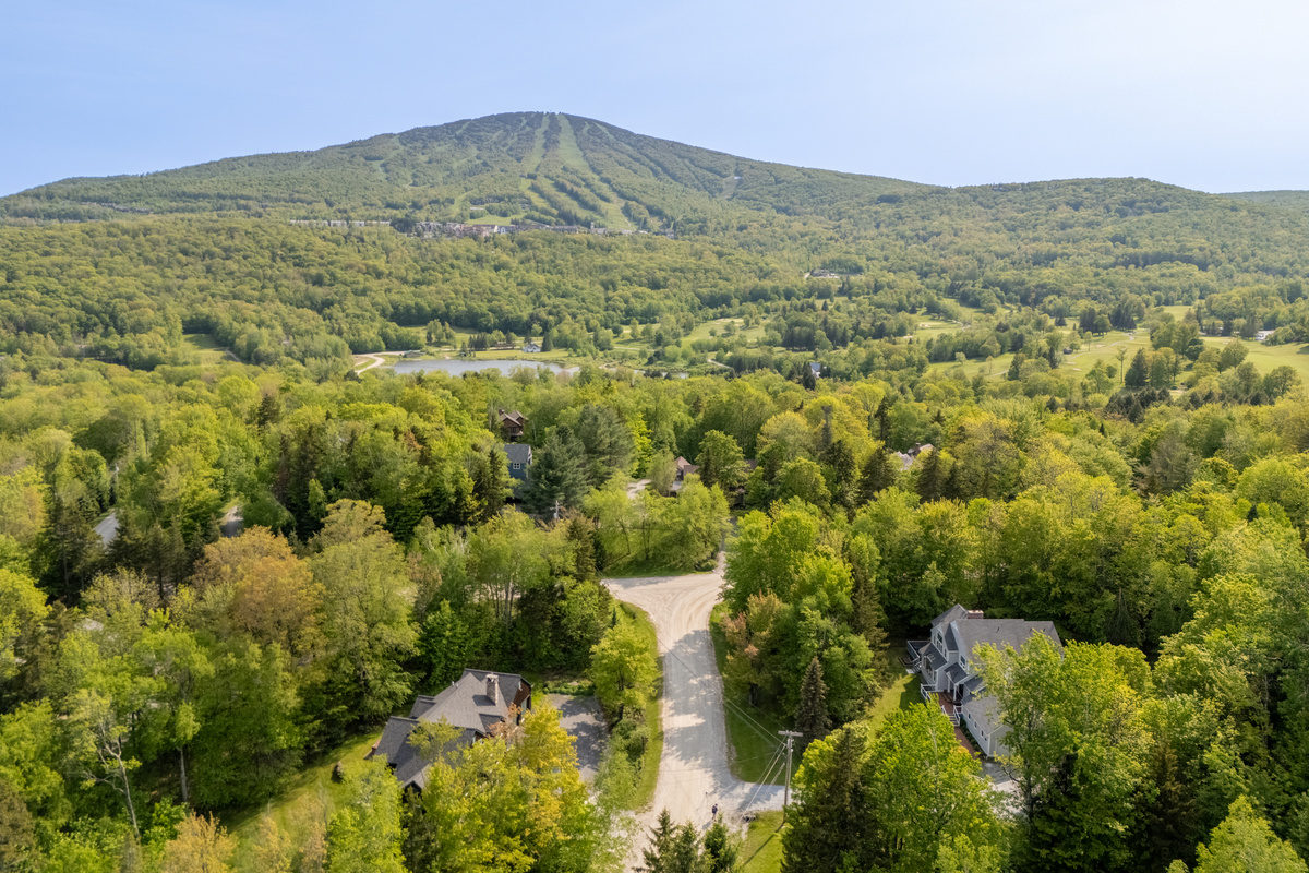 Aerial view of First Chair Lair with Stratton Mountain ski trails rising behind the home in Winhall, Vermont