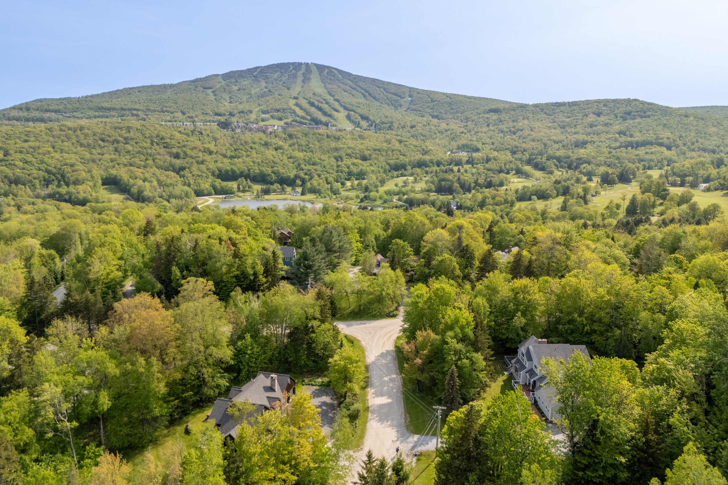 Aerial view of First Chair Lair with Stratton Mountain ski trails rising behind the home in Winhall, Vermont