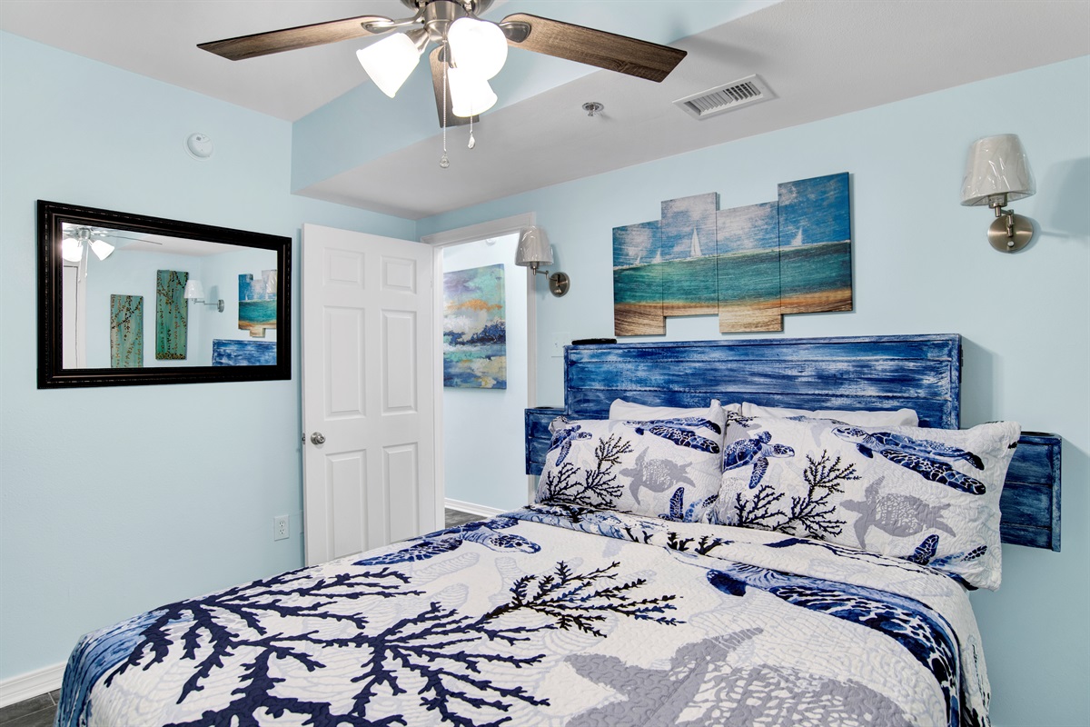 Bedroom 2 has a queen bed with built in side tables, ceiling fan, chest of drawers, and wall mounted smart TV