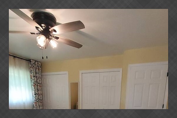 This sunny master suite feels spacious and uplifting, with soft yellow walls and floral curtains that brighten the room. Two roomy his-and-her closets offer generous storage, and natural light creates a peaceful, cheerful vibe all day.