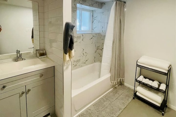 Clean and stocked bathroom with bath and shower and fresh towels provided.