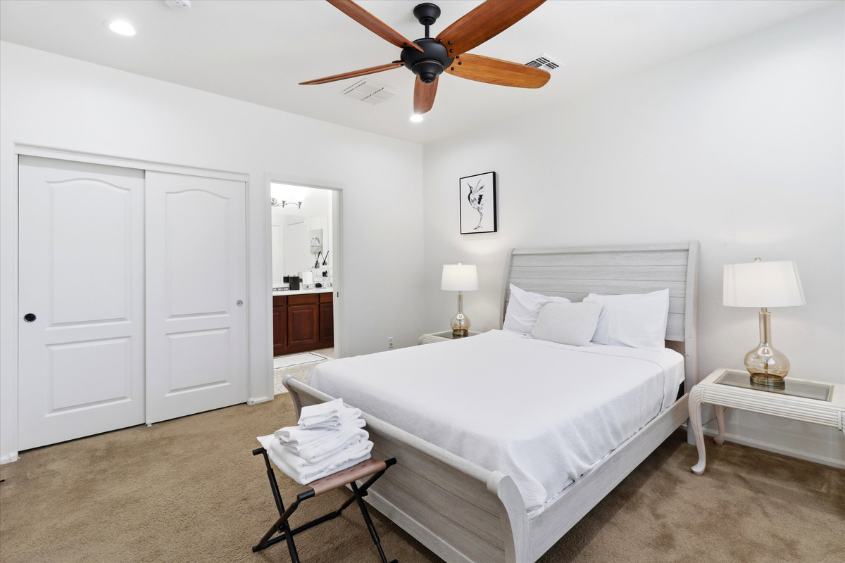 Bedroom with fresh linens, ceiling fan, closet storage, and easy access to the bathroom.

