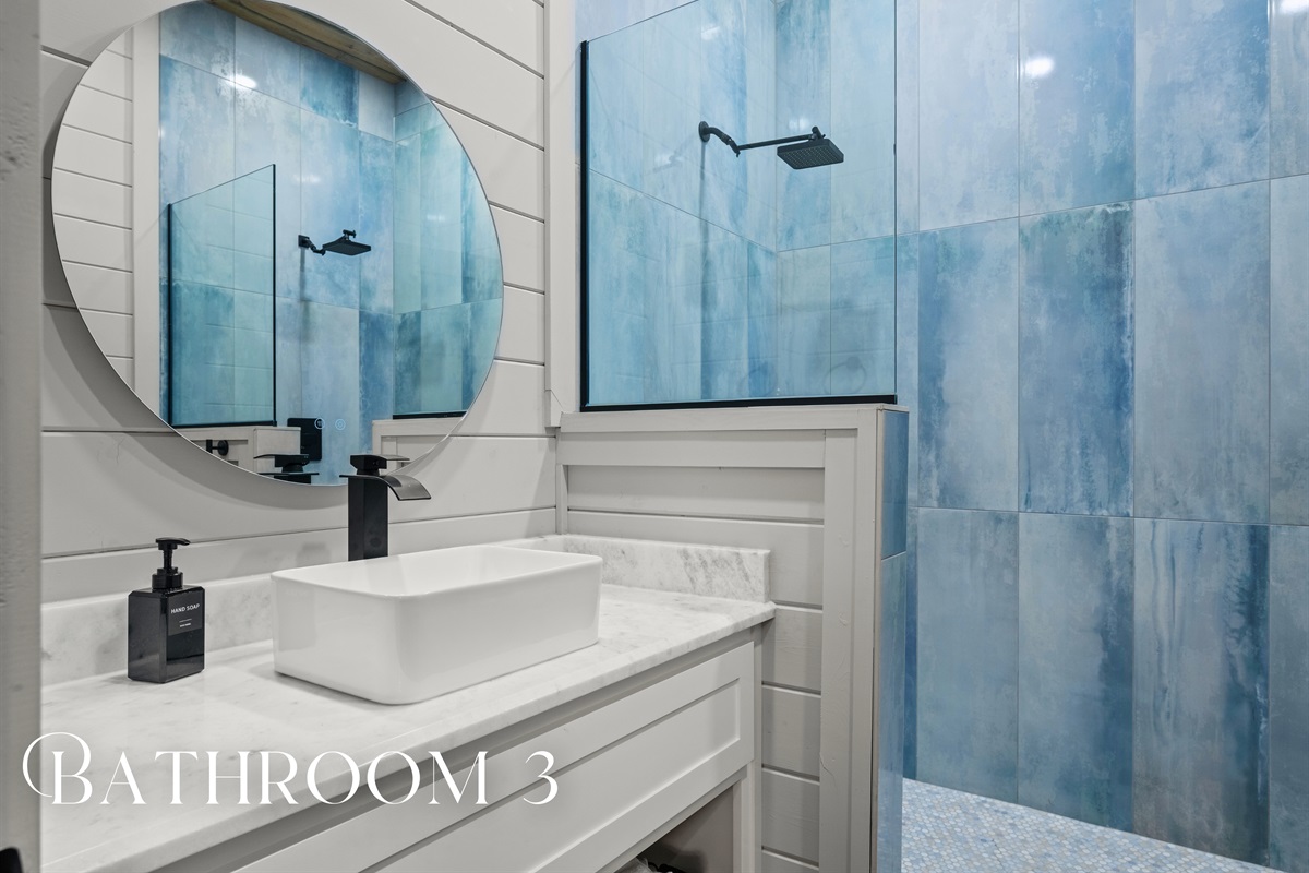 Blue-tiled walls and crisp finishes make this bathroom feel fresh, vibrant, and full of character.