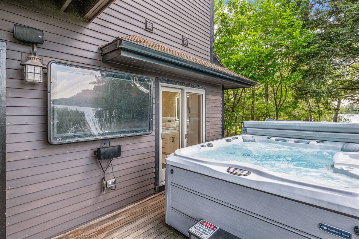 Hot tub with seating for 8 with its own tv, overlooking Lake Winnipesuakee and the mountain range in the distance