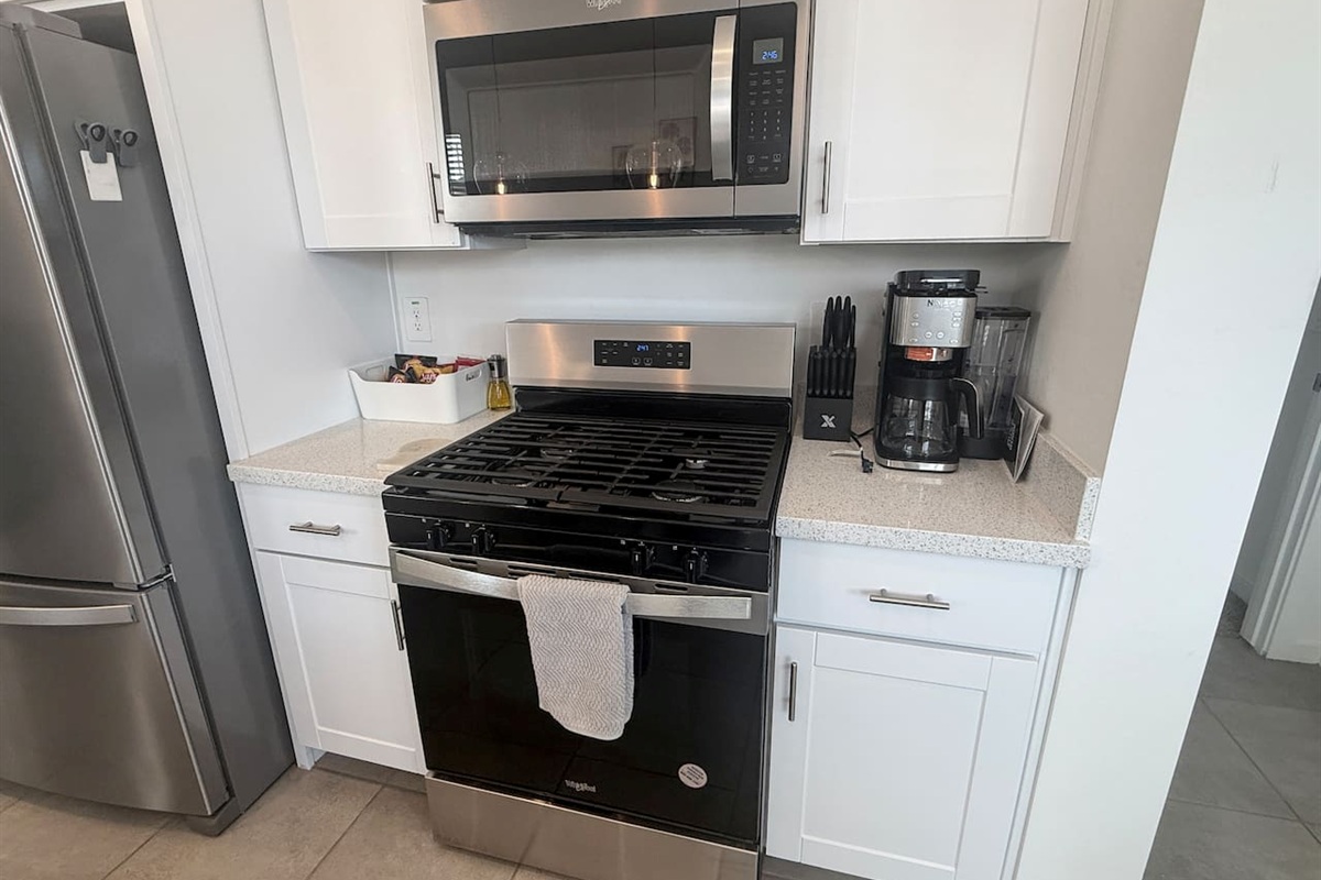Kitchen stove area with microwave, coffee maker, and cabinets
