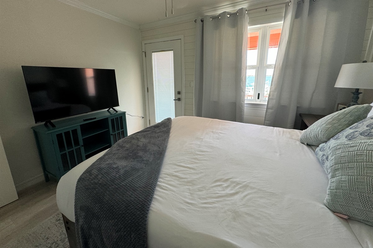Second bedroom with queen bed and smart tv, balcony access