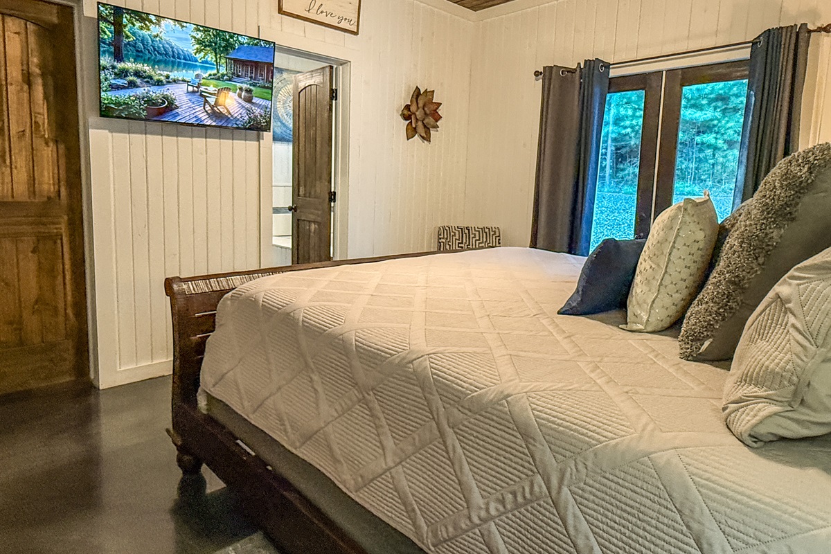 Relax in the king suite with direct deck access, smart TV, and cozy bedding for restful nights in the pines.