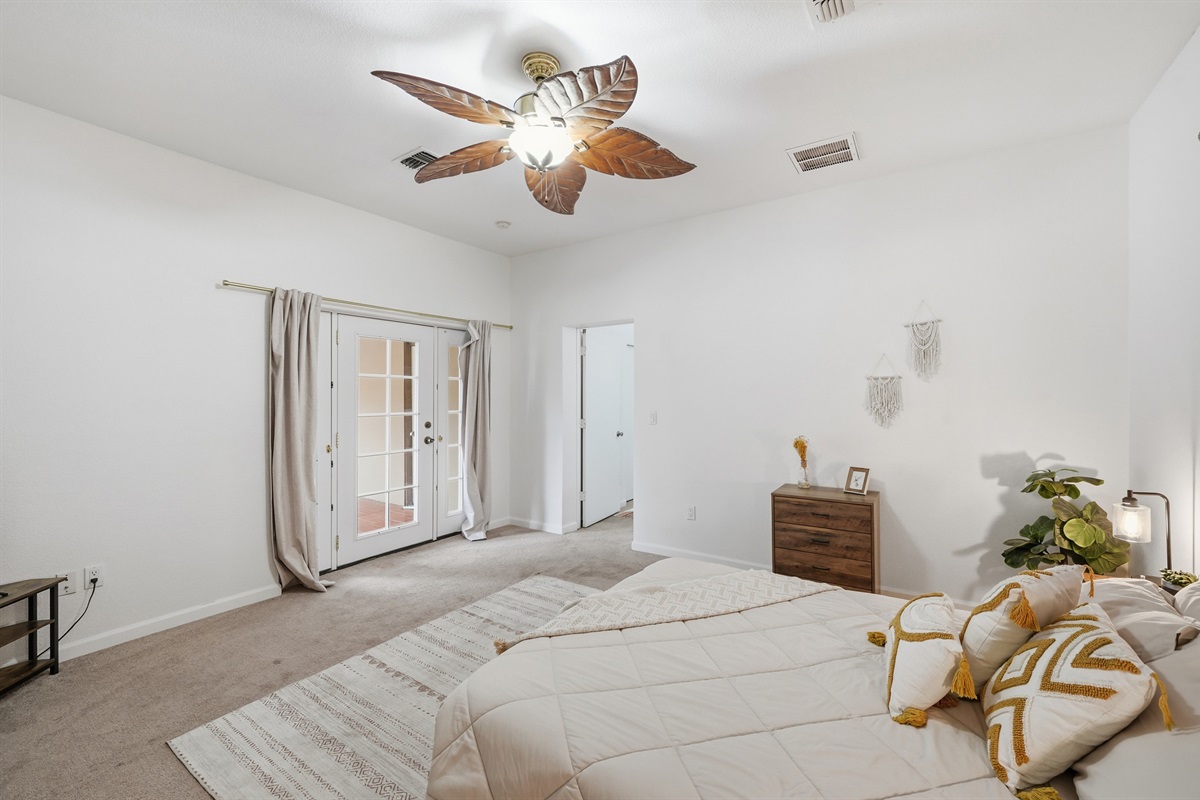 This spacious bedroom offers a peaceful desert-inspired retreat, complete with cozy linens, tribal accents, and a tropical ceiling fan for added charm.
