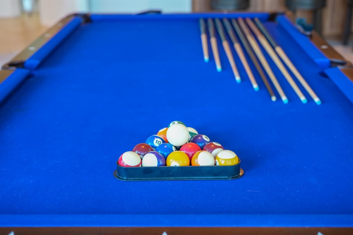 Close-up of the pool table setup with cues and racked balls, ready for friendly competition.
