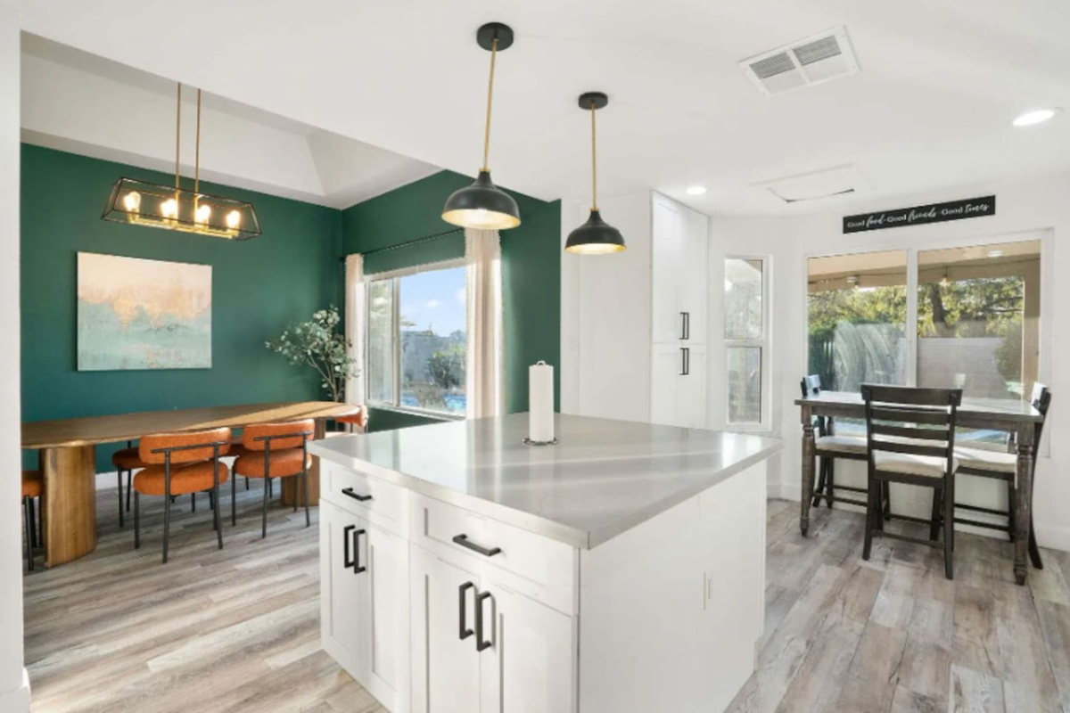 Multi-zone room with forest green accent wall, chef's island, workspace, and scenic window views.