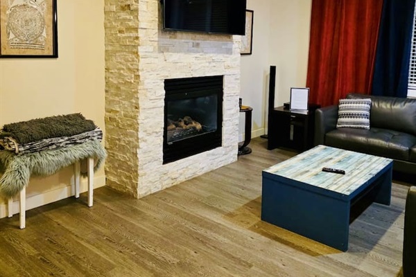 Cozy living room with stone fireplace, smart TV, and plush seating